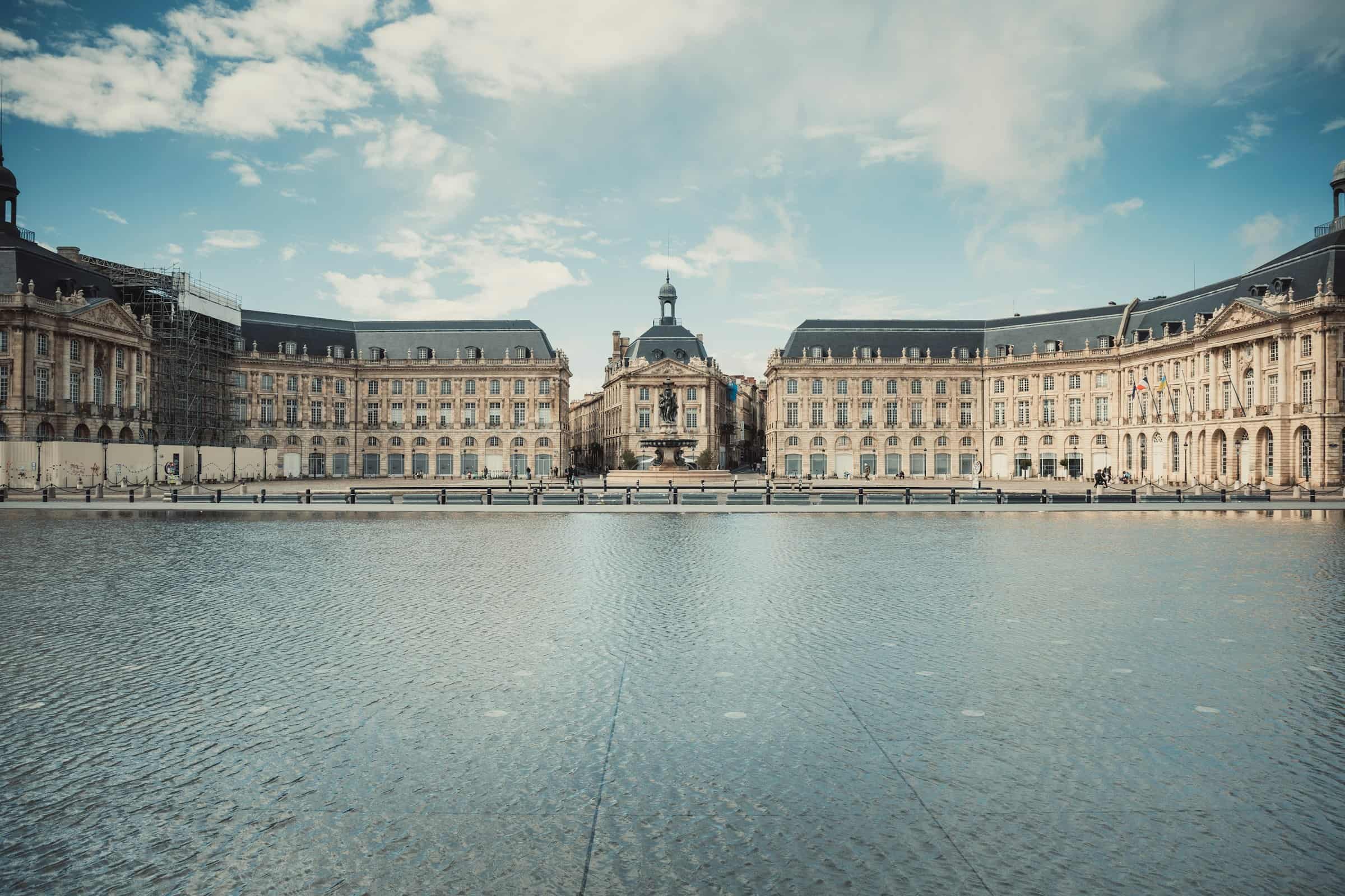 La Place de la Bourse à Bordeaux et son miroir d’eau, en plein jour, sous un ciel voilé