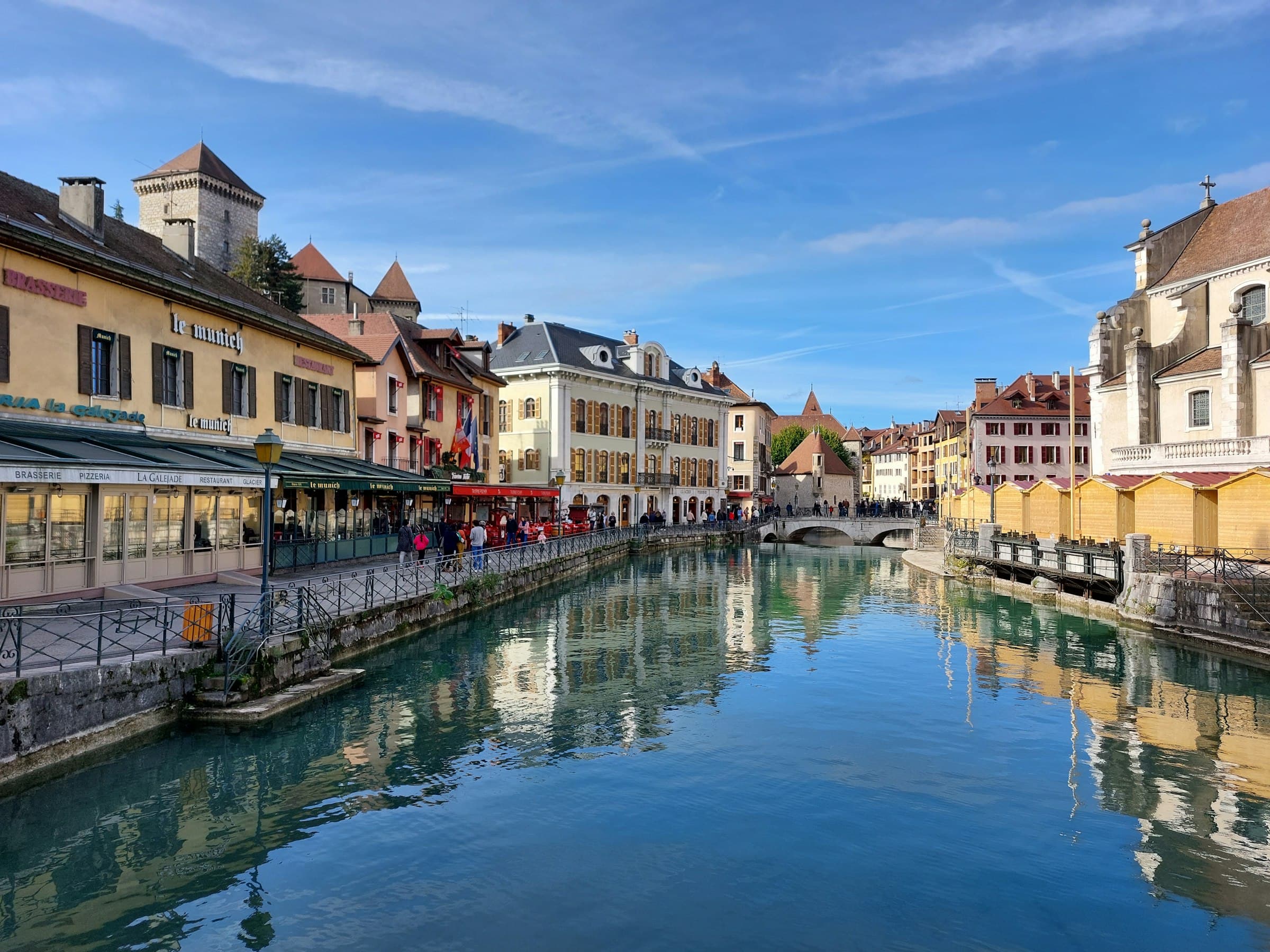 Le Thiou traversant la vieille ville d’Annecy, terrasses et façades le long du quai, sous un ciel bleu