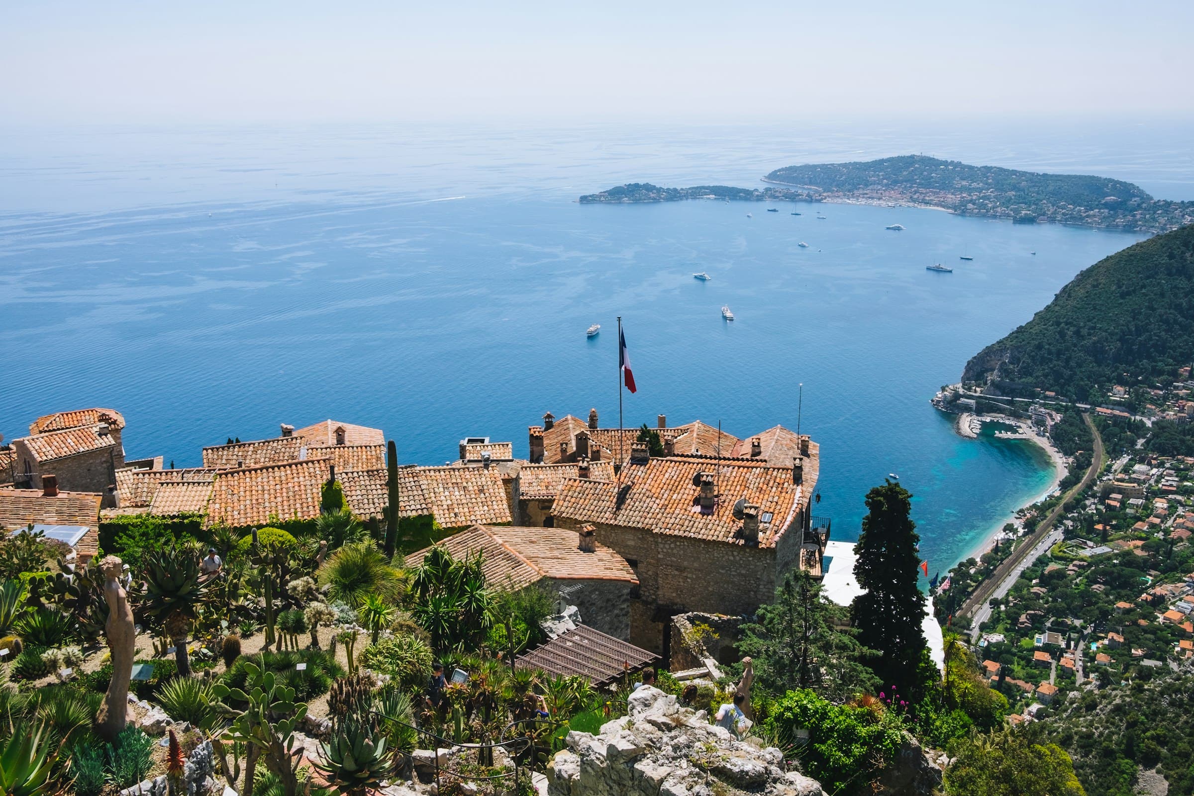 Les toits de tuiles du village perché d’Èze vus depuis la hauteur, la Méditerranée et la côte s’étirant en contrebas